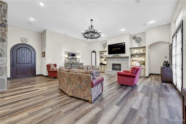 living room with an inviting chandelier, recessed lighting, a fireplace, arched walkways, and wood finished floors