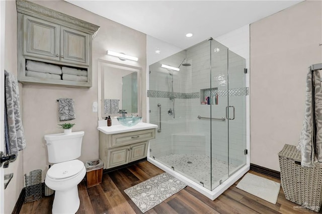 bathroom with toilet, recessed lighting, a shower stall, vanity, and wood finished floors