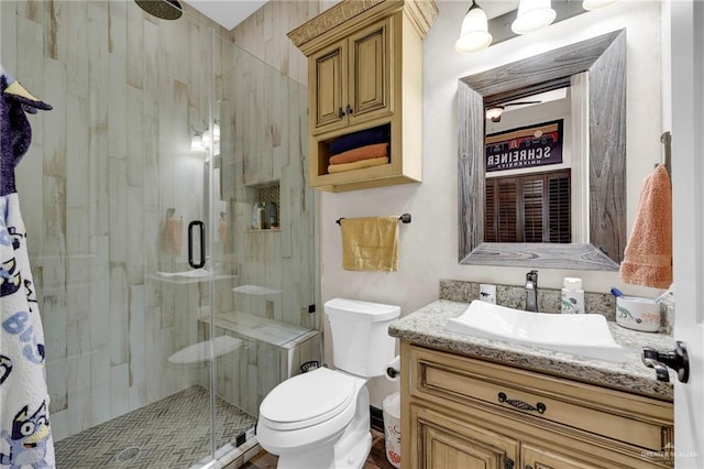 bathroom featuring toilet, a shower stall, and vanity
