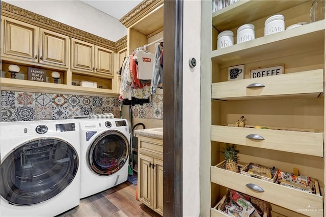 clothes washing area featuring separate washer and dryer, wood finished floors, and cabinet space
