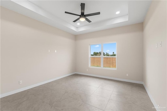 spare room with a tray ceiling and ceiling fan