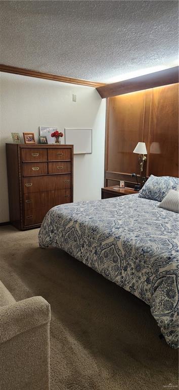bedroom featuring a textured ceiling, carpet floors, and ornamental molding