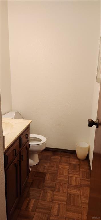 bathroom with toilet, vanity, and baseboards