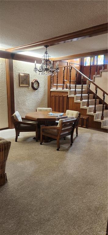 rec room with a textured ceiling, a textured wall, carpet, a chandelier, and crown molding
