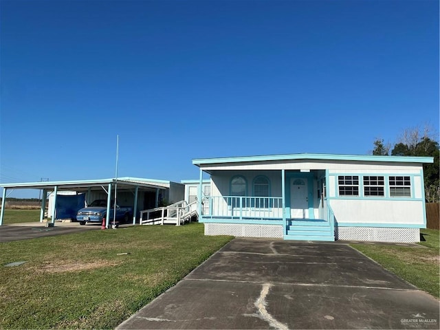 manufactured / mobile home featuring covered porch, a front yard, and a carport