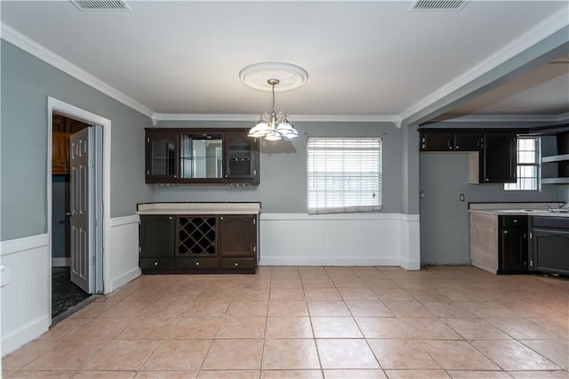 unfurnished dining area featuring a notable chandelier, sink, light tile patterned floors, and crown molding