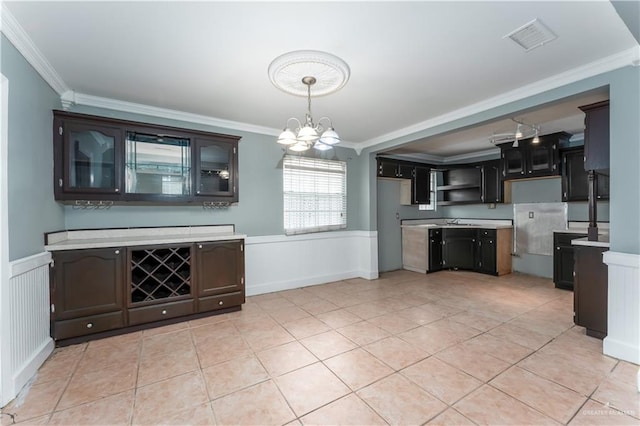 kitchen featuring a notable chandelier, dark brown cabinets, decorative light fixtures, and ornamental molding