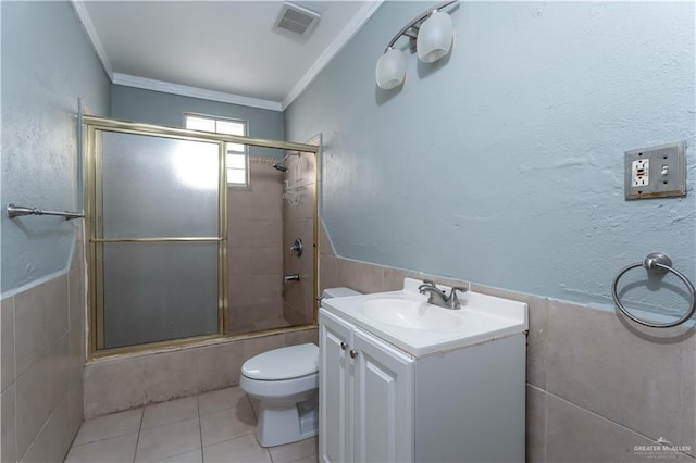 full bathroom featuring tile patterned flooring, crown molding, toilet, vanity, and tile walls