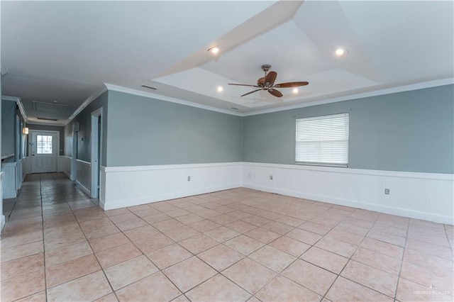 tiled empty room with a raised ceiling, crown molding, and ceiling fan