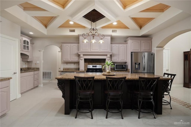 kitchen featuring coffered ceiling, a kitchen island, appliances with stainless steel finishes, and tasteful backsplash