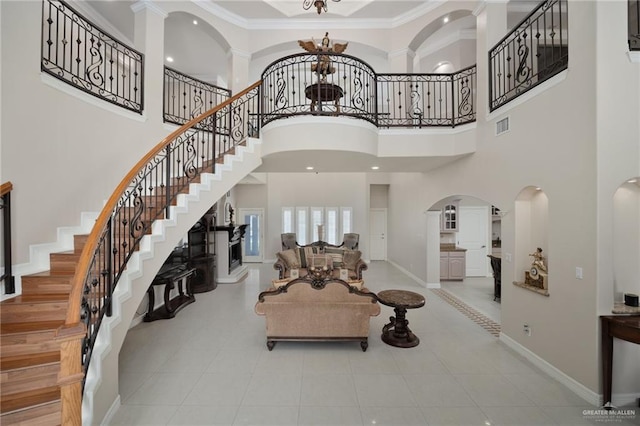 foyer with an inviting chandelier, a towering ceiling, and ornamental molding