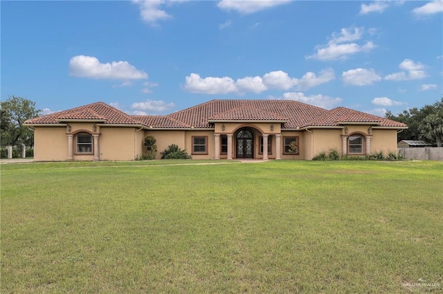 mediterranean / spanish home with fence, stucco siding, a front lawn, and french doors
