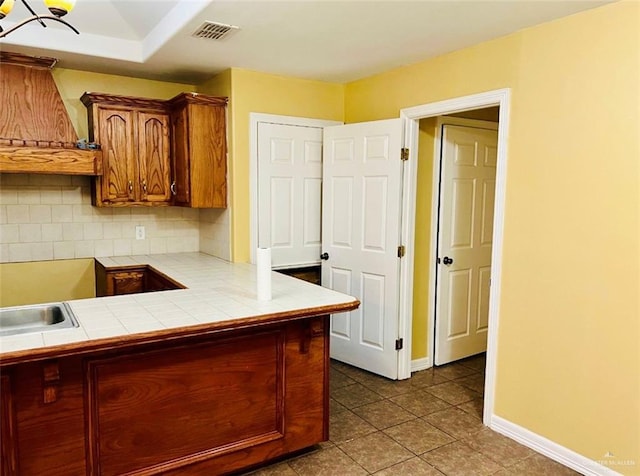 kitchen featuring tile countertops, tile patterned floors, sink, tasteful backsplash, and custom range hood