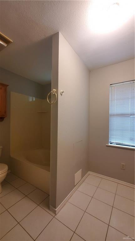 bathroom with tile patterned floors, shower / bathing tub combination, toilet, and a textured ceiling