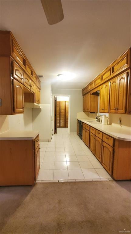 kitchen with light tile patterned floors, black dishwasher, and sink