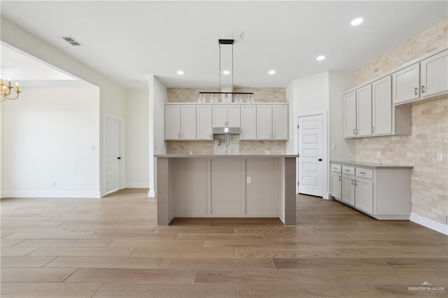 403 Faith Dr, La Feria, TX 78559 - kitchen featuring tasteful backsplash, a notable chandelier, light wood-style floors, and under cabinet range hood