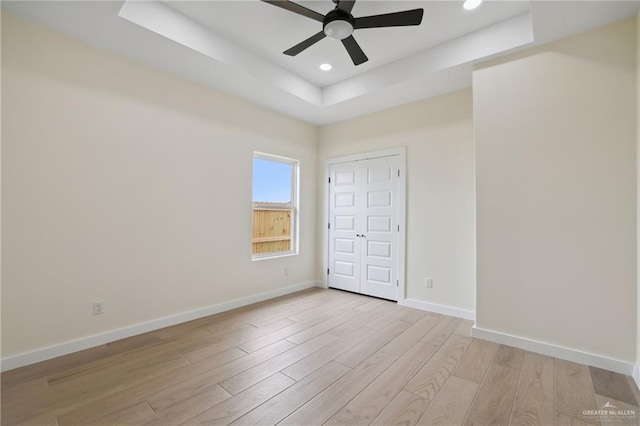 403 Faith Dr, La Feria, TX 78559 - unfurnished bedroom featuring recessed lighting, light wood-style floors, baseboards, a ceiling fan, and a tray ceiling