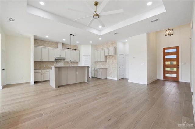 403 Faith Dr, La Feria, TX 78559 - unfurnished living room with light wood finished floors, a raised ceiling, ceiling fan, and visible vents