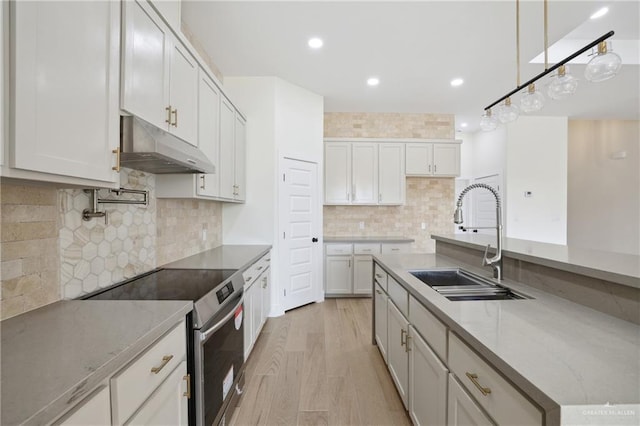 403 Faith Dr, La Feria, TX 78559 - kitchen with recessed lighting, a sink, under cabinet range hood, stainless steel electric range oven, and light wood-style flooring