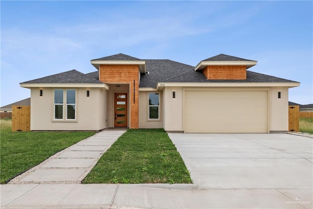 403 Faith Dr, La Feria, TX 78559 - prairie-style home with a front lawn, an attached garage, concrete driveway, and stucco siding