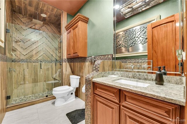 bathroom featuring vanity, toilet, a shower with door, and tile walls