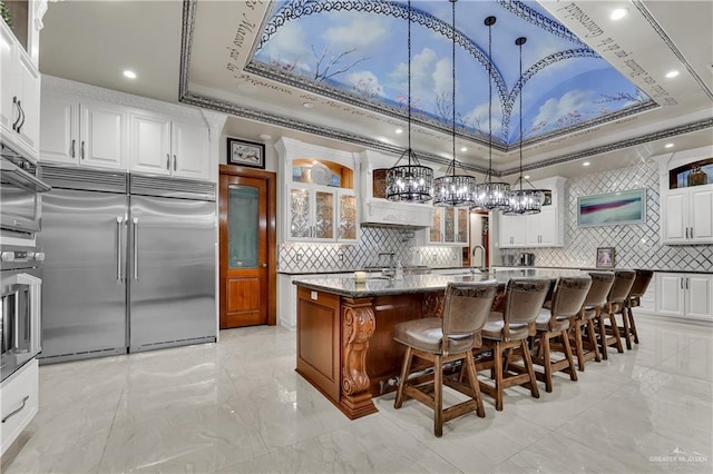 kitchen featuring pendant lighting, dark stone countertops, a kitchen island with sink, and appliances with stainless steel finishes