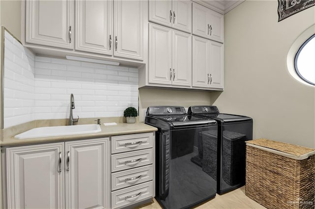 laundry area featuring cabinets, washing machine and clothes dryer, and sink