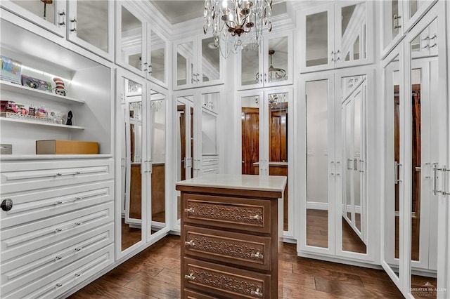 walk in closet with a chandelier and dark hardwood / wood-style floors