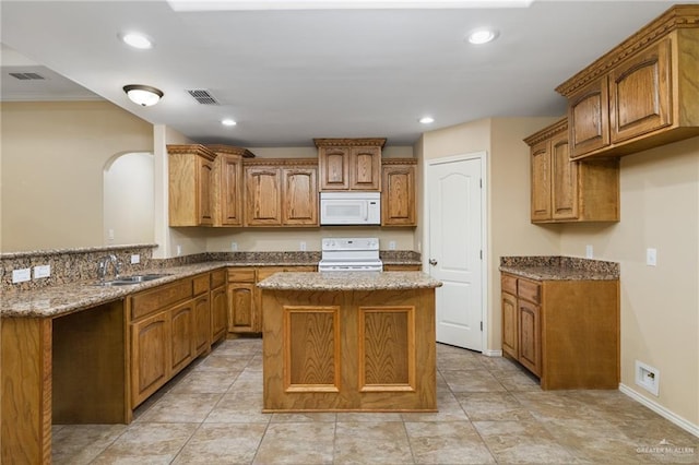 kitchen featuring sink, a center island, kitchen peninsula, stone counters, and white appliances