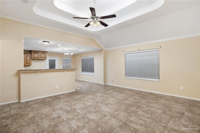 unfurnished living room with ceiling fan with notable chandelier and a tray ceiling