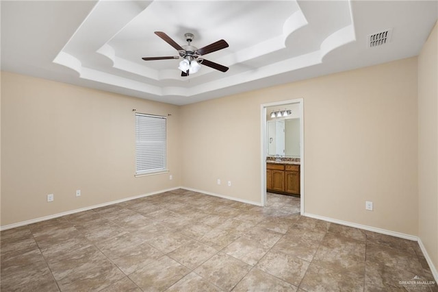 spare room with ceiling fan and a tray ceiling