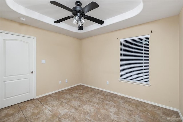 spare room with ceiling fan and a tray ceiling