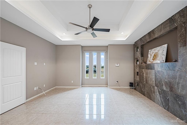 unfurnished room with ceiling fan and a tray ceiling