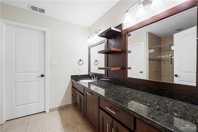 bathroom featuring tile patterned flooring, vanity, and tiled shower