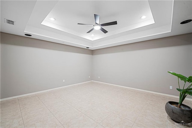 tiled spare room with ceiling fan and a raised ceiling