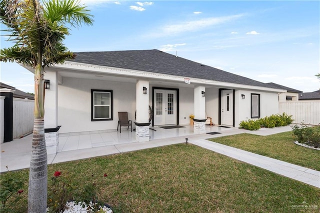 rear view of property featuring a lawn and french doors