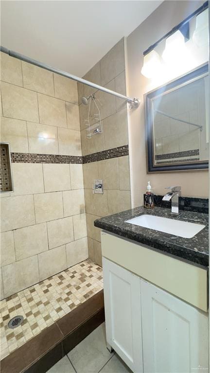 bathroom featuring tiled shower, vanity, and tile patterned flooring