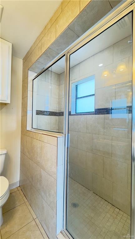 bathroom featuring tile patterned floors, a shower with door, and toilet