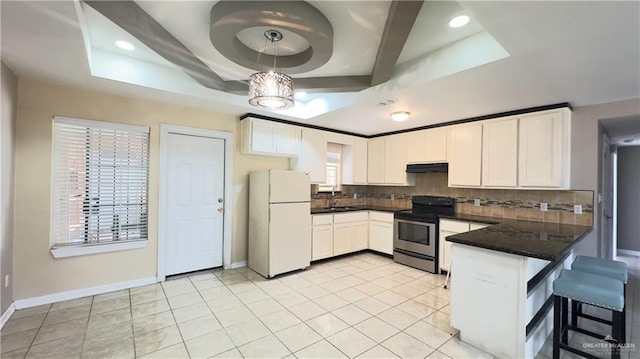 kitchen with stainless steel electric stove, white refrigerator, a raised ceiling, and white cabinetry