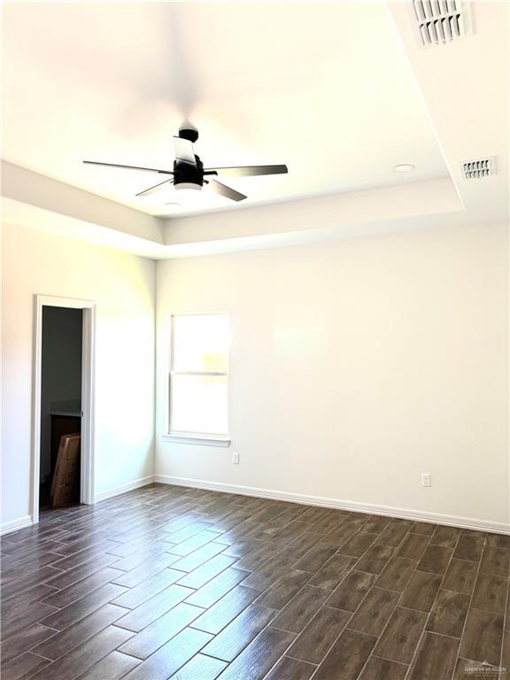 1804 Hailey St, San Juan, TX 78589 - unfurnished room featuring dark wood-style flooring, visible vents, a ceiling fan, and a raised ceiling