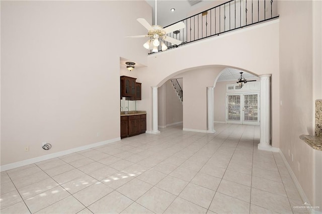 2206 Kings Dr, Edinburg, TX 78539 - unfurnished living room featuring ceiling fan, arched walkways, a towering ceiling, decorative columns, and light tile patterned floors