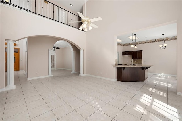 2206 Kings Dr, Edinburg, TX 78539 - unfurnished living room with ceiling fan, light tile patterned floors, arched walkways, a sink, and a high ceiling