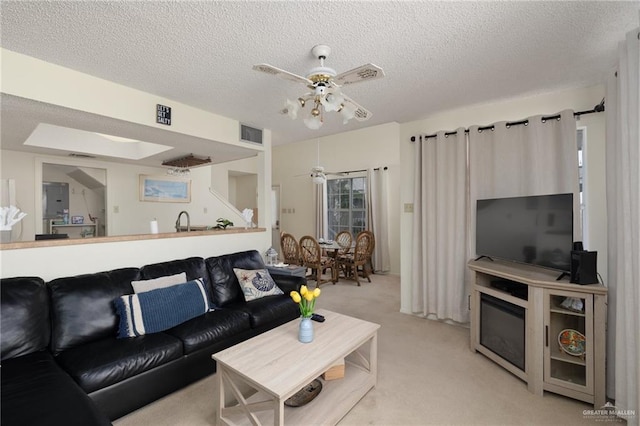 living area featuring visible vents, light colored carpet, ceiling fan, and a textured ceiling