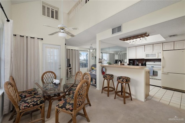 dining space featuring ceiling fan, visible vents, and light colored carpet