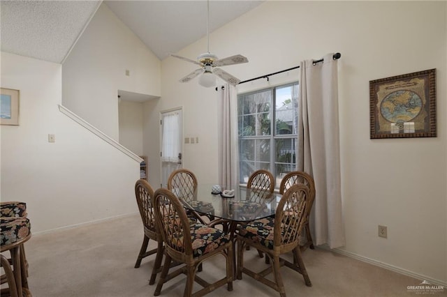 dining area with high vaulted ceiling, light colored carpet, ceiling fan, and baseboards