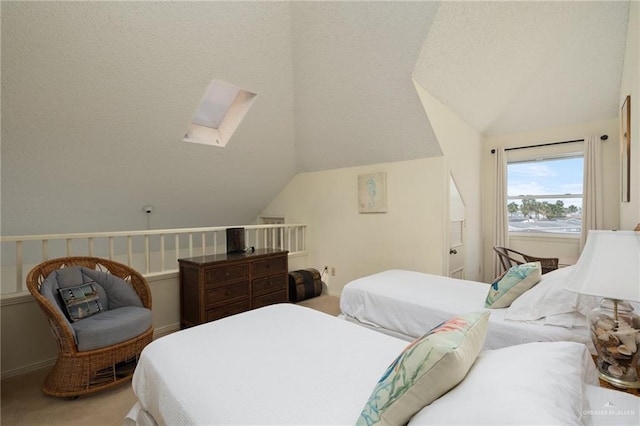 bedroom with a textured ceiling, vaulted ceiling with skylight, and carpet