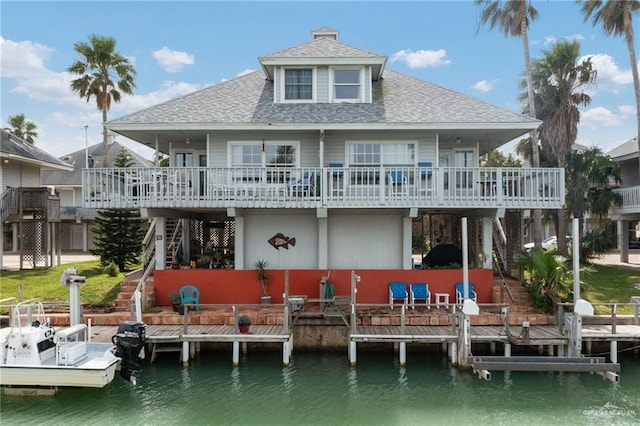 rear view of property with stairs, roof with shingles, a deck with water view, and boat lift