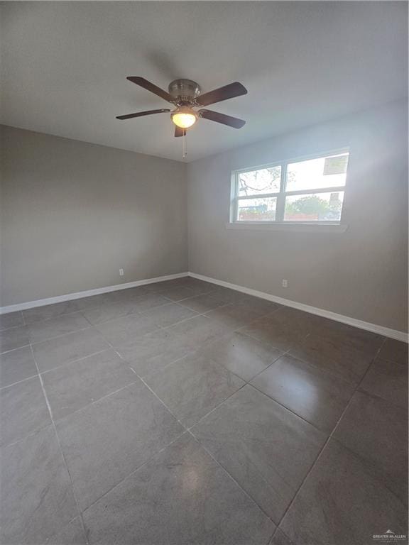 tiled spare room featuring ceiling fan and baseboards