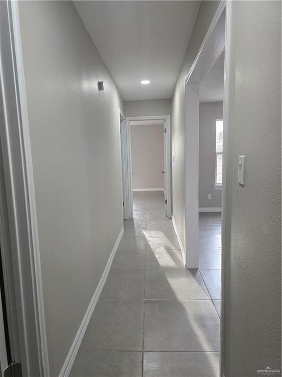 hallway with light tile patterned flooring and baseboards