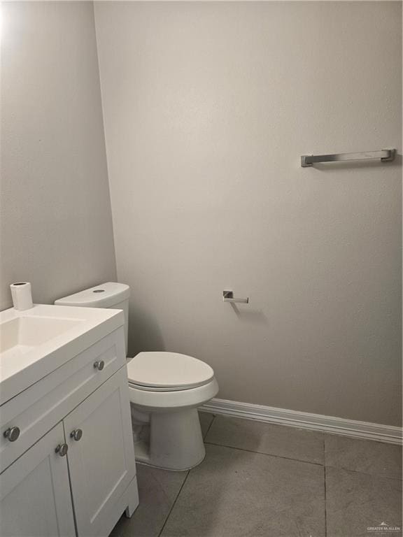 bathroom featuring vanity, toilet, baseboards, and tile patterned flooring